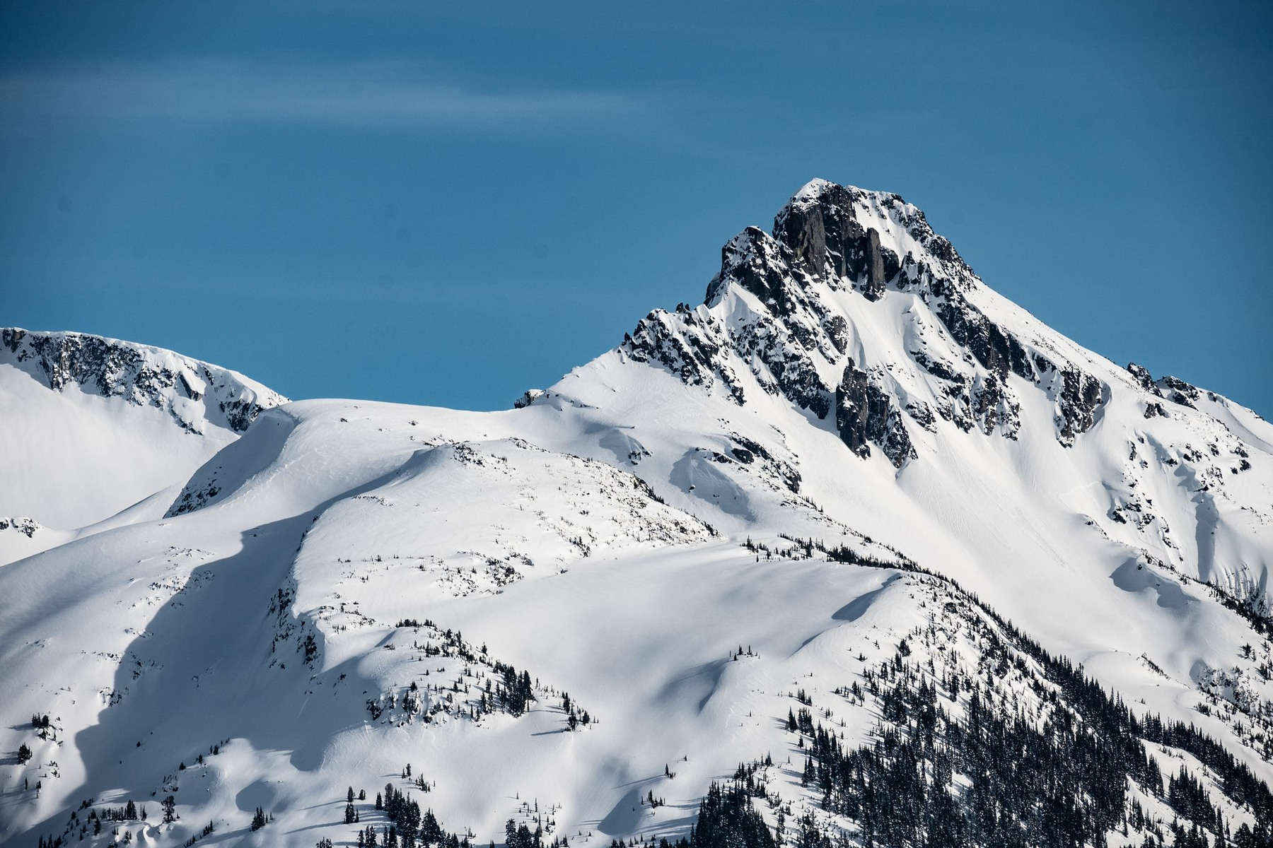 蓝天下的雪山,明亮积雪与岩壁阴影形成层次